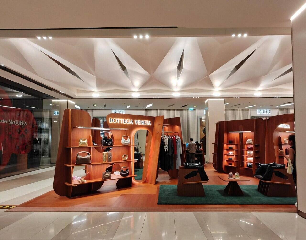 Retail display joinery in warm timber, with open shelving, a brand sign and concealed lighting