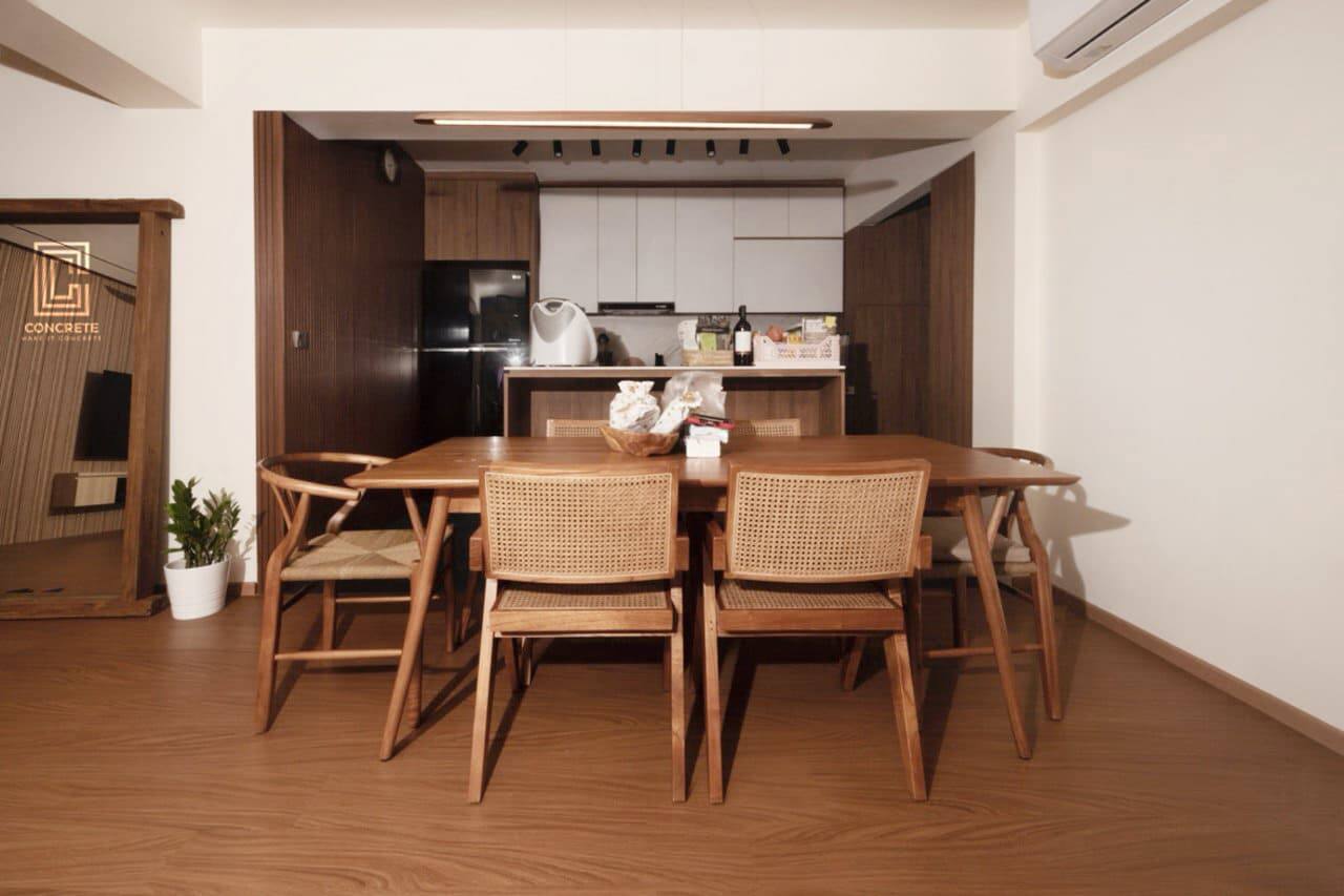 Dining room with a solid timber table, woven rattan-back chairs and a dark timber kitchen behind